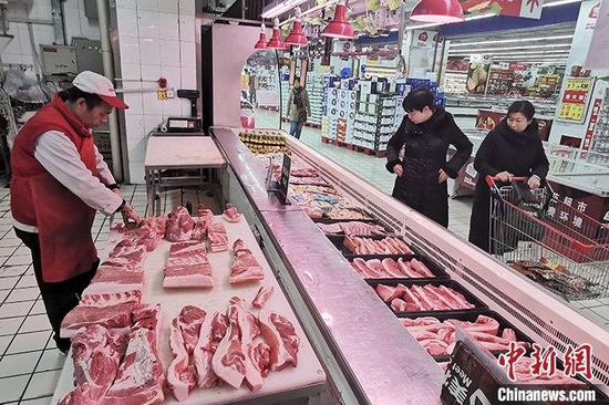 12月16日，山西太原，超市工作人员分解猪肉。中新社记者 张云 摄